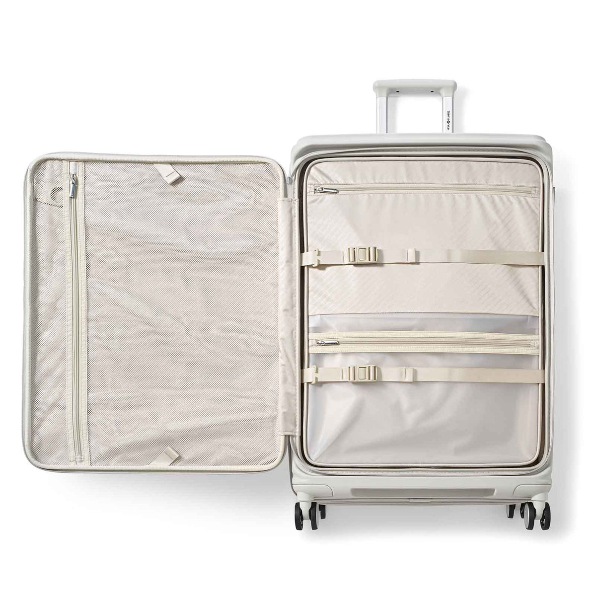 A hard-shell suitcase shown open from above, revealing a light beige interior with multiple zip compartments and elastic straps. The exterior shell is a pale metallic silver-gray, and the handle and wheels are visible against a clean white background.