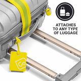 Yellow luggage tag attached to a suitcase with a rolling suitcase in the background.