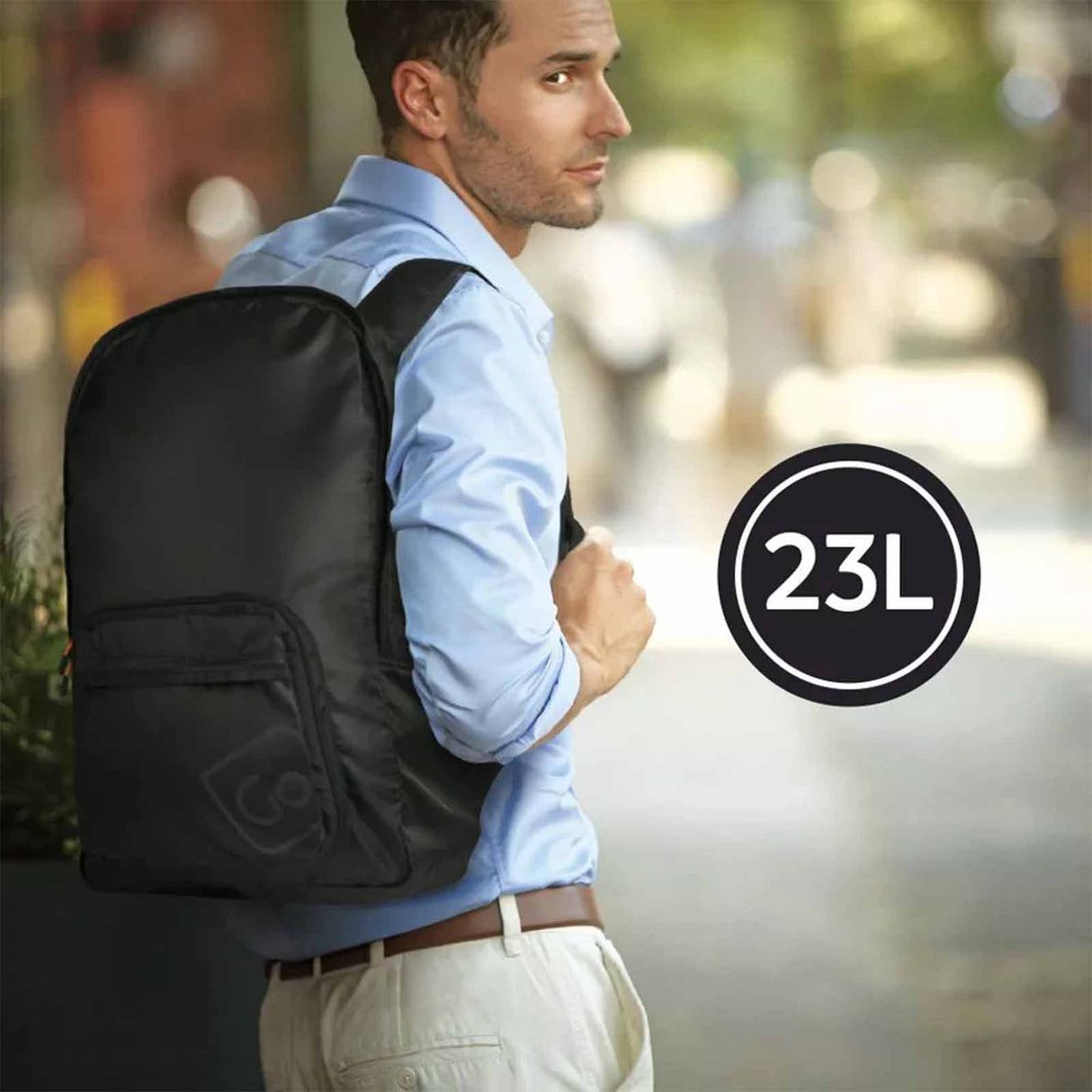 Man wearing a black backpack with a '23L' label, standing outdoors.