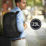 Man wearing a black backpack with a '23L' label, standing outdoors.