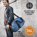 Man holding a blue duffel bag with an adjustable shoulder strap and 34L capacity label on a textured wall background.