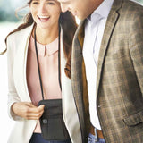 Woman holding a black crossbody bag with a man in a plaid jacket, both smiling outdoors.