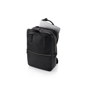 A black leather backpack shown at an angle on a white background, with a silver laptop partially tucked into the top zip compartment.