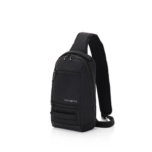 A black Samsonite brand sling backpack with a single shoulder strap and multiple zippered compartments, shown from a three-quarter angle on a solid white background.