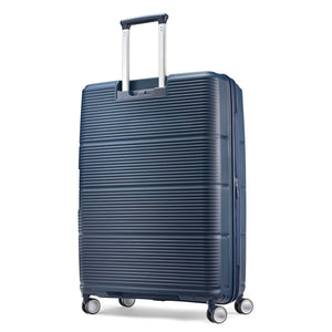 A navy blue hardshell spinner suitcase with a ribbed design, featuring an extended telescopic handle and four multi-directional wheels, shown on a plain white background.