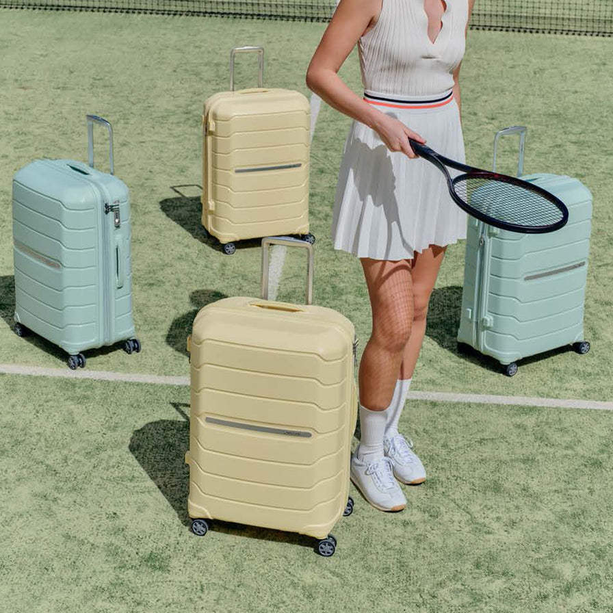 Woman holding a tennis racket with four suitcases on a tennis court