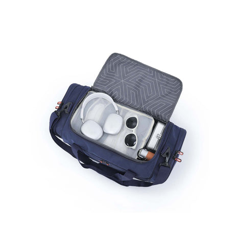 An open navy blue duffel bag with a transparent zippered compartment, shown on a white background. Inside, a gray geometric-patterned lid.