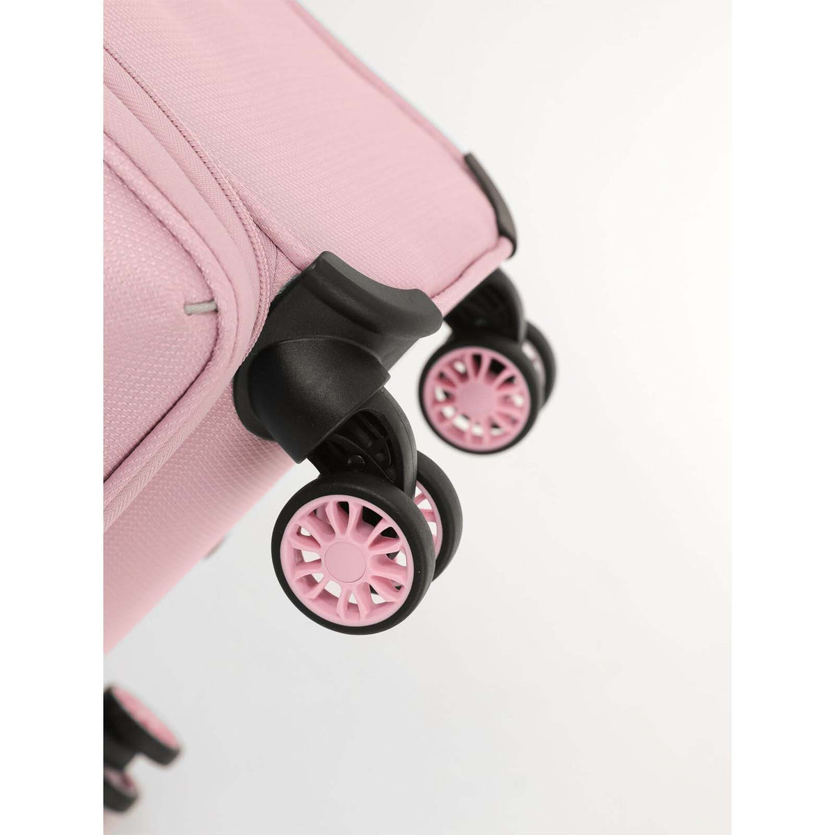 Close-up of a pink suitcase with black spinner wheels and pink wheel centers on a clean white background.