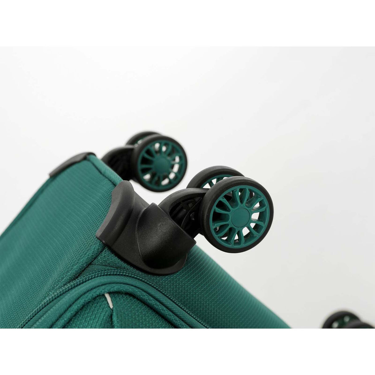 Close-up of an Emerald Green suitcase with black spinner wheels and pink wheel centers on a clean white 