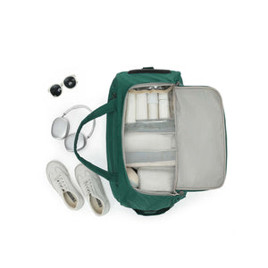 An Emerald Green Carry-On bag shown from above with its interior open, filled with travel items including white toiletry bottles, a gray organizer insert, and a small cooler. White sneakers, silver headphones, and black sunglasses are placed beside it on a clean white background.